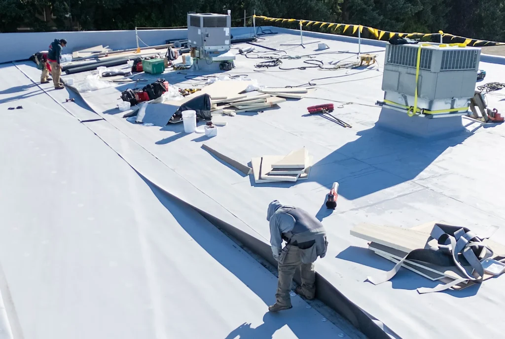 Workers installing roofing materials outdoors.
